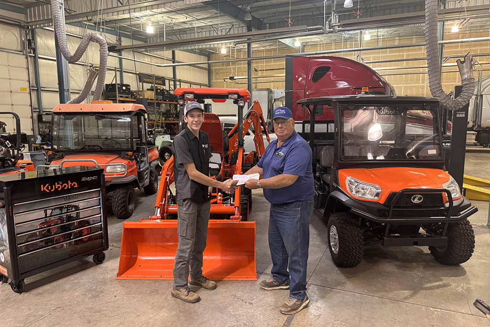 A man is giving documents to a Chemeketa Diesel Technology student in front of Kubota branded equipment. The two are shaking hands. The implication is the man is giving the student paperwork to start a job after their completion of the Diesel Technology program.